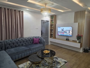 Ein modernes Wohnzimmer mit einem grauen Sofa, einem schwarzen Couchtisch und einem an der Wand befestigten Fernseher.