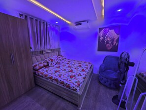 Ein Schlafzimmer mit einem Bett, einem Kleiderschrank, einem Sessel und einer Wand-Klimaanlage.