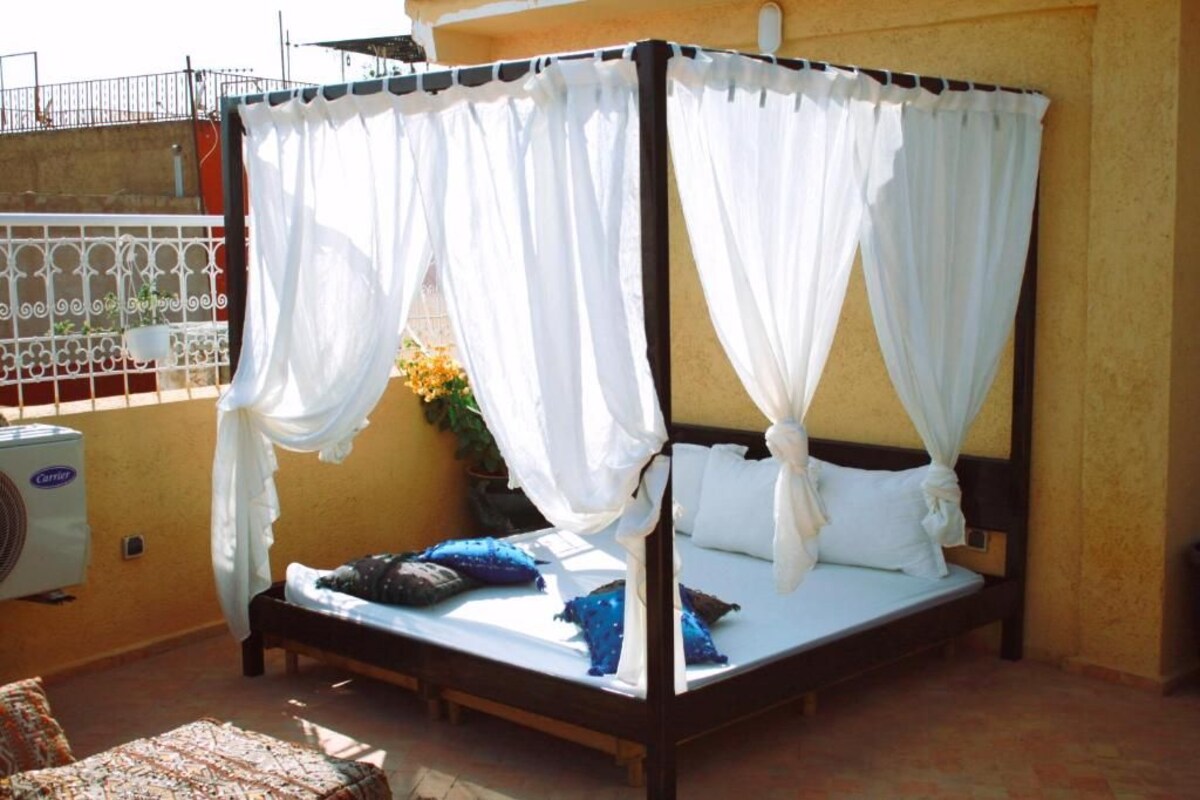 A four-poster bed with white drapes, a wooden headboard, and multiple pillows.