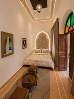Un dormitorio con una cama, un espejo, una mesita y un adorno en la pared.