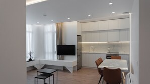 Una cocina moderna con armarios blancos, horno empotrado y encimera de mármol.