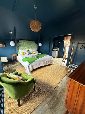 A bedroom with a bed, green armchair, and a wooden dresser. - Stunning semi- rural cottage with a huge bed! (Wadhurst)