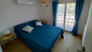 Un dormitorio con una cama, una mesita de noche con una lámpara y una ventana con cortinas.