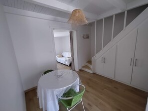 A room with a round table, a green chair, a staircase, and a bed in the background. - DIRECT BEACH ACCESS HOUSE WITH TERRACE (Poggio-Mezzana)