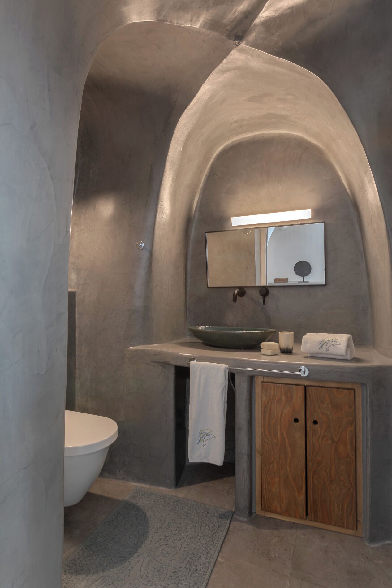 A bathroom with a built-in sink, a mirror, and a toilet.