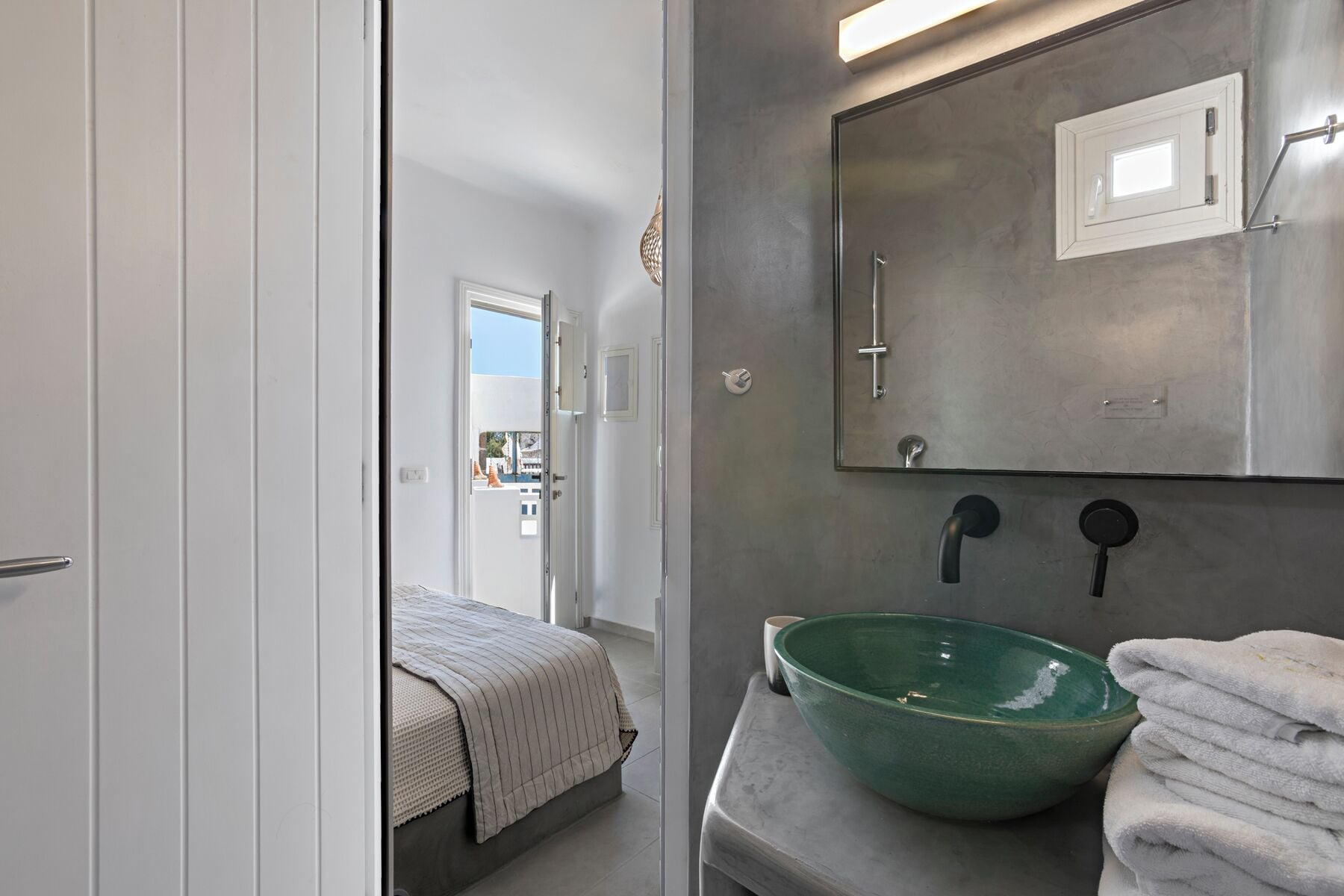 A bathroom with a green bowl sink, a towel rack, and a mirror.