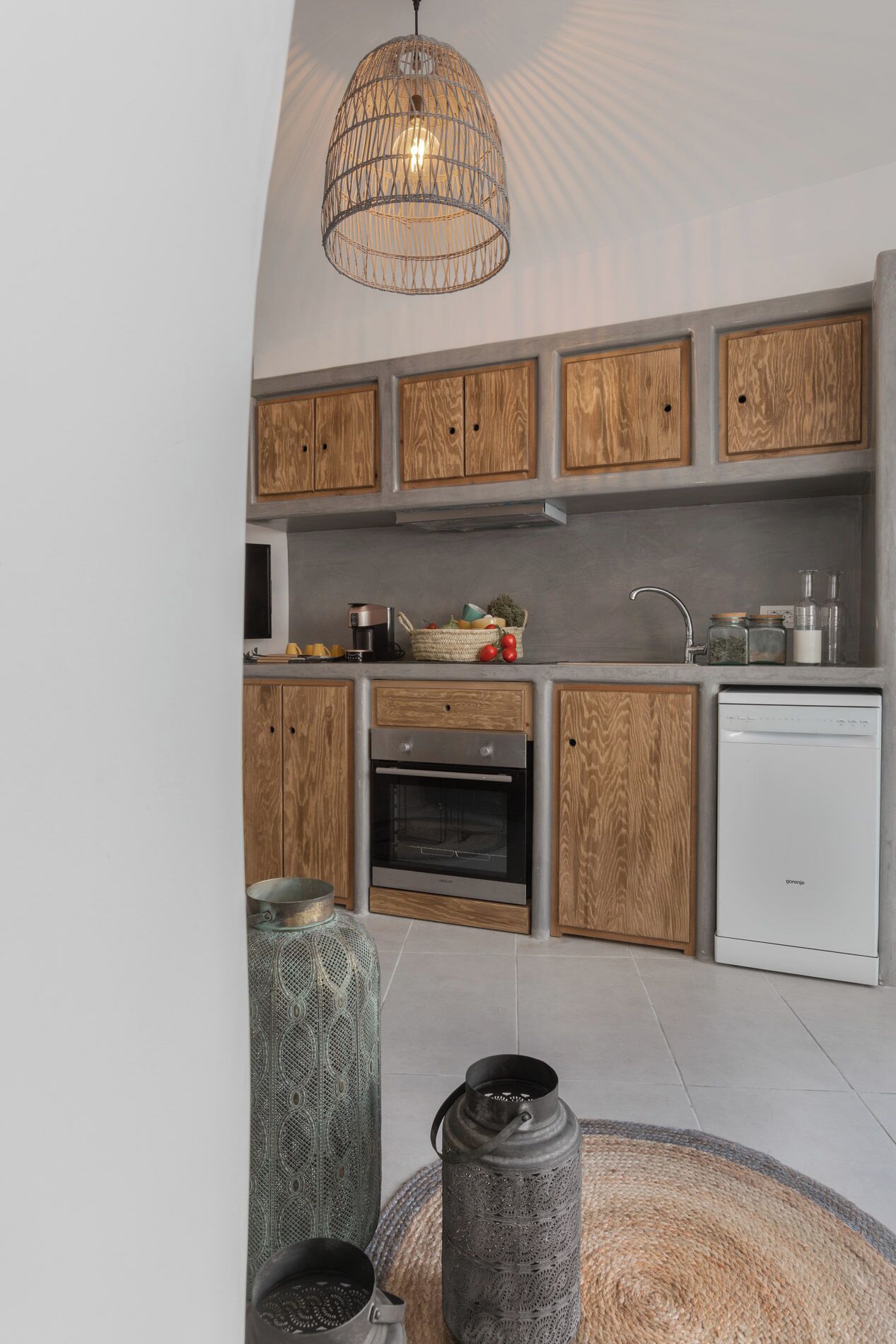 A modern kitchen with wooden cabinets, a built-in oven, a dishwasher, and a hanging light fixture.