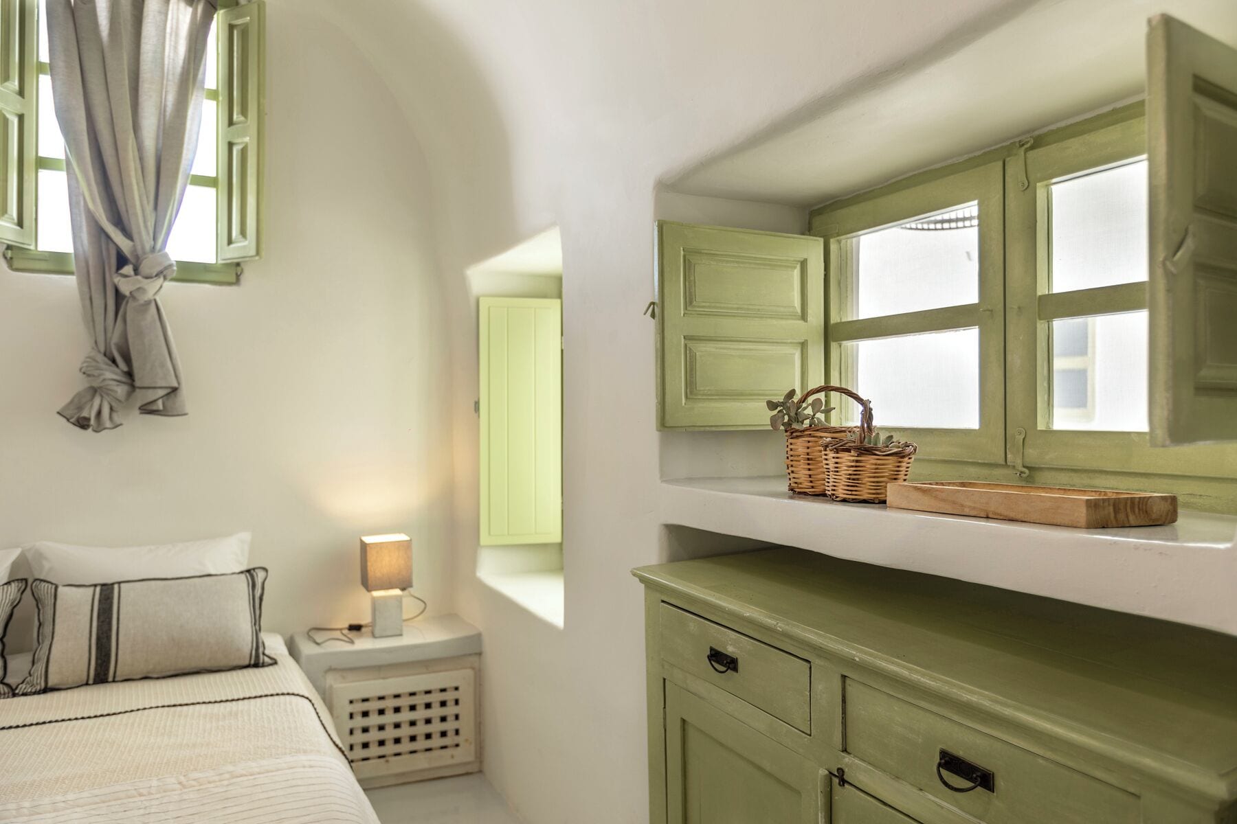 Un dormitorio con cama, mesita de noche, lámpara y ventana con cortinas.