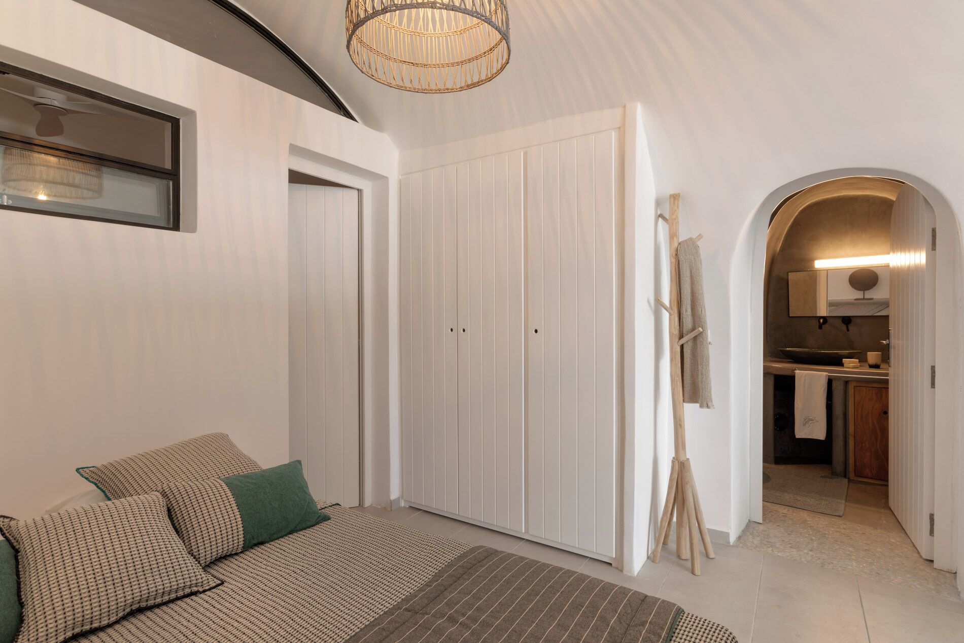 Une chambre à coucher comprenant un lit, une armoire et un coin cuisine, le tout visible à travers une arche.