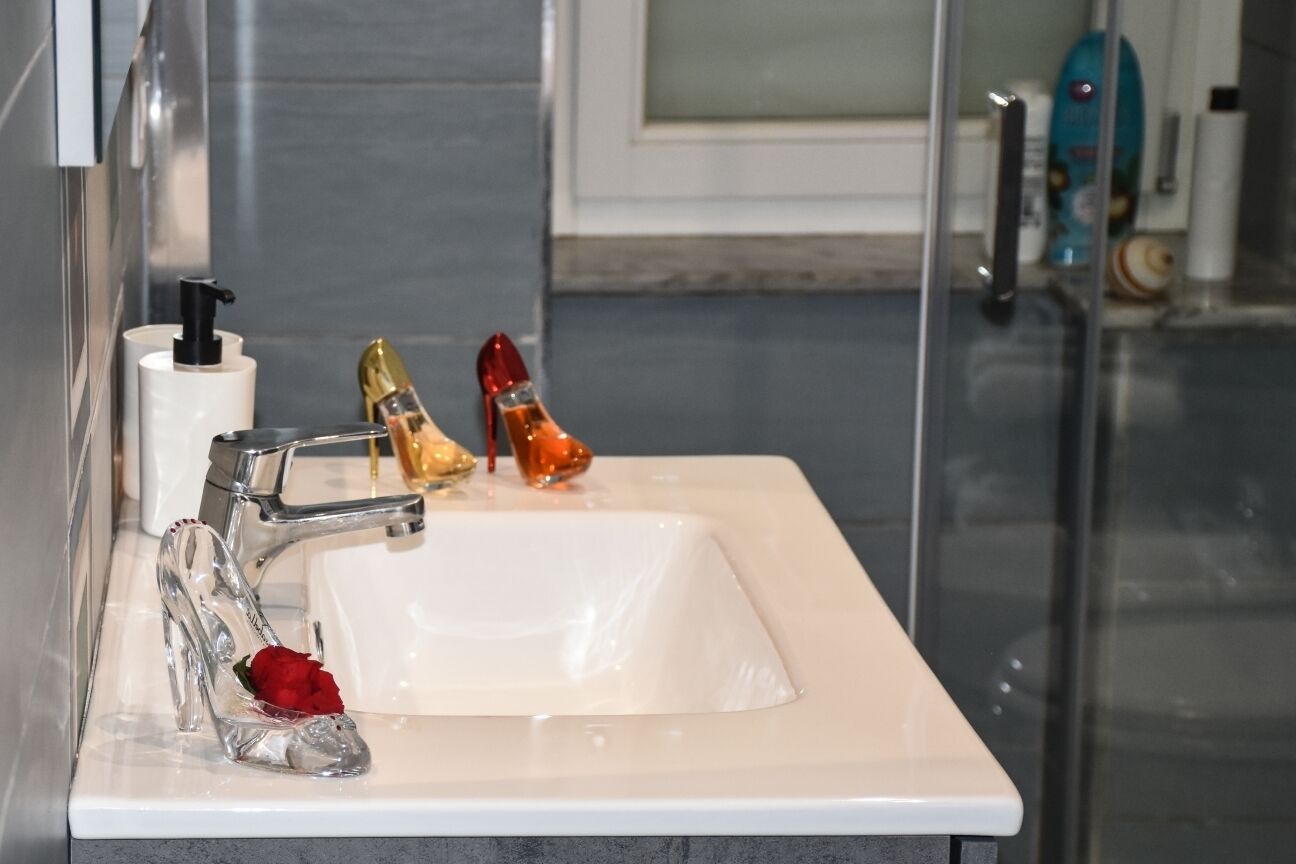 Une salle de bain avec un lavabo blanc, un robinet chromé et deux bouteilles décoratives.