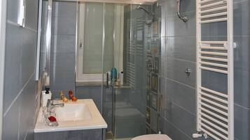 Ein Badezimmer mit einer Duschkabine, einem weißen Waschbecken und einer Toilette.