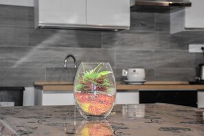 A kitchen with a modern design, featuring a glass vase with a plant on a marble countertop. - House Nonno Viky (Volla)