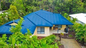 Una casa con techo azul, rodeada de abundante vegetación.