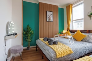 A modern bedroom with a bed, a vanity with lights, a potted plant, and a window with curtains. - Stylish 3-Bed Apartment with Side Sea View in Bognor Regis (Bognor Regis)