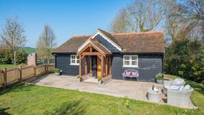 A two-story house with a dark exterior, a pitched roof, and a wooden porch. - The Gate Lodge - One Bed Cottage - Pet Free - Nr Finchingfield & Saffron Walden (Little Bardfield)