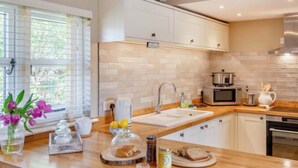 A modern kitchen with a wooden countertop, white cabinets, a sink, a microwave, and a stove. - The Gate Lodge - One Bed Cottage - Pet Free - Nr Finchingfield & Saffron Walden (Little Bardfield)