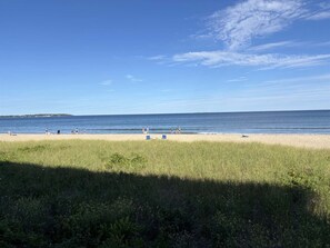 A beach with people, grass, and a clear sky. - Sandy Shores Oceanfront: 1-BR condo in Old Orchard Beach with stunning ocean views. (Old Orchard Beach)
