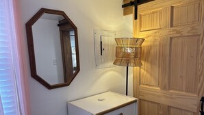 Een badkamer met een witte wastafel, een spiegel, een wandlamp en houten deuren.
