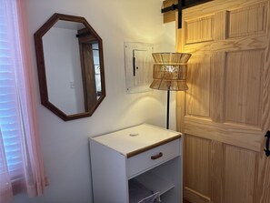 A bathroom with a white sink, a mirror, a wall-mounted light fixture, and wooden doors. - Enjoy ocean views at Mainely Millie's, a charming 3-bedroom cottage in Camp Ellis, Saco, ME. (Saco)