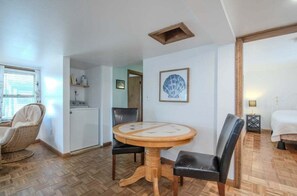 A room with a round wooden table, two chairs, a bed, a small table with a lamp, and a framed picture on the wall. - Enjoy ocean views at Mainely Millie's, a charming 3-bedroom cottage in Camp Ellis, Saco, ME. (Saco)