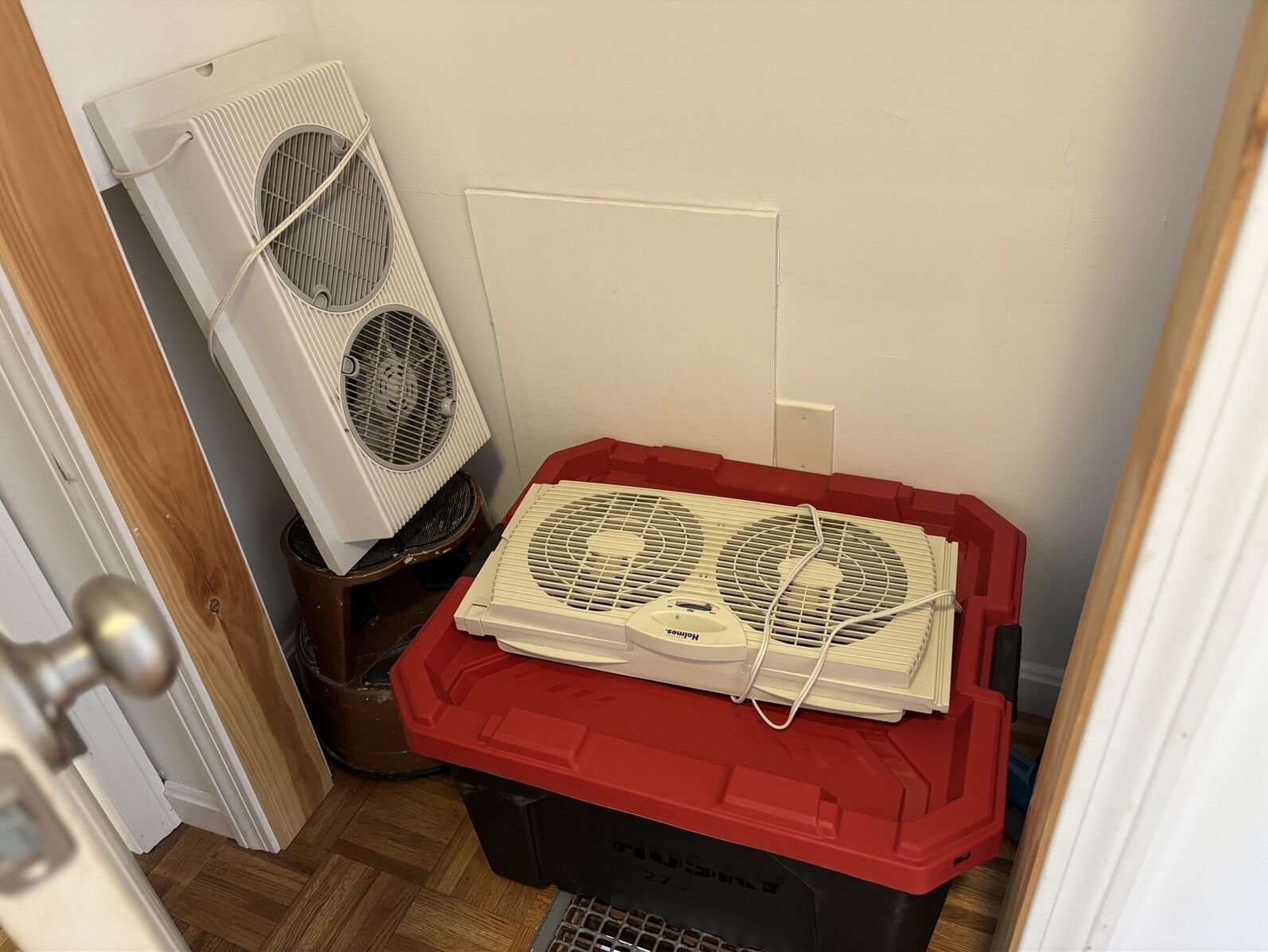 Een kleine kamer met een witte radiator, een rode opbergbak en een deur.