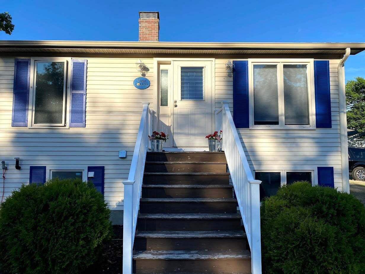 Une maison à deux étages avec un porche à l’avant, un escalier menant à l’entrée et une boîte aux lettres sur la porte d’entrée.