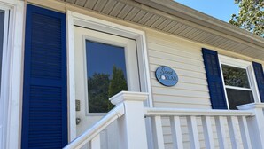 A house with a porch, a door with a window, and a sign that reads "Sand Dollar". - Experience coastal charm at Sand Dollar, a spacious 4-bedroom retreat in Ferry Beach, Saco, ME. (Saco)