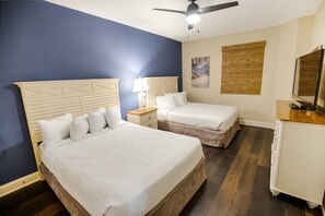 Ein Hotelzimmer mit zwei Betten, einem Nachttisch, einer Kommode und einem Deckenventilator.