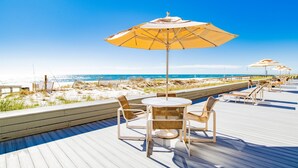Una terraza de madera con mobiliario exterior y sombrillas con vista a la playa.