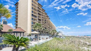 Un hotel de varios pisos con balcones, zona de piscina y vista a la playa.