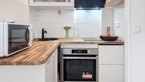 Une cuisine moderne avec des meubles blancs, un four à micro-ondes encastré, un lave-vaisselle et un four en acier inoxydable.