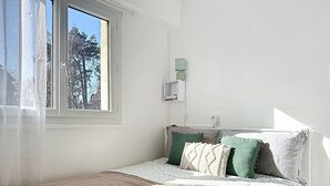 Une chambre à coucher avec un lit, une fenêtre et une lampe fixée au mur.