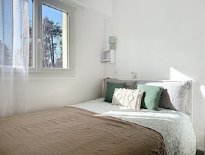 A bedroom with a bed, a window, and a wall-mounted lamp. - Apartment Sand by Interhome (Deauville-Trouville)