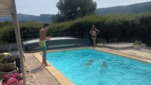 Ein Schwimmbecken mit klarem, blauem Wasser, umgeben von Steinplatten und Blumenbeeten.