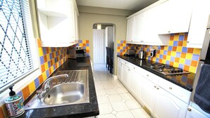 Una cocina con armarios blancos, encimera negra y salpicadero de azulejos coloridos.