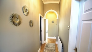 Un pasillo con alfombra estampada, espejos decorativos y una puerta blanca.