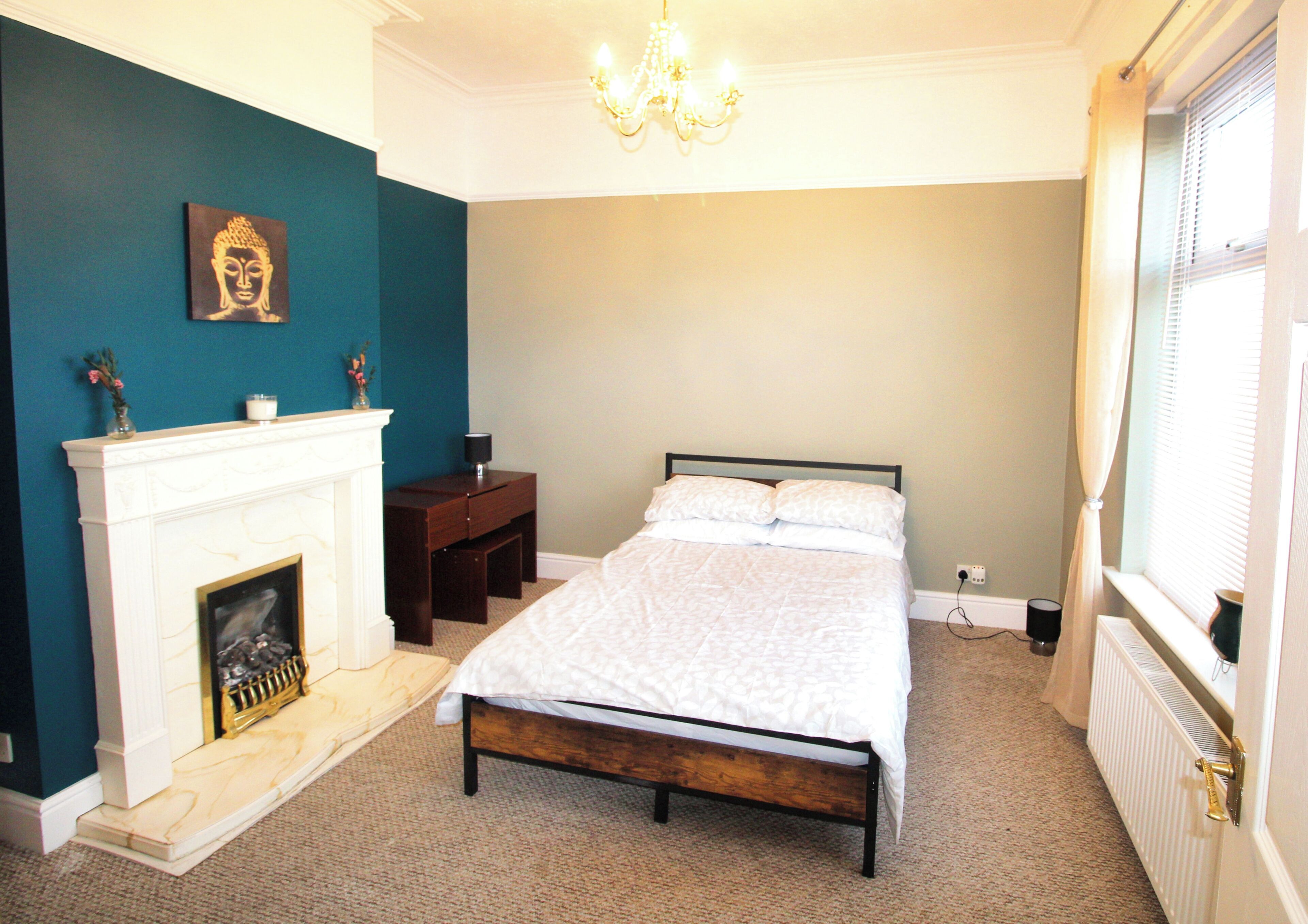 A bedroom with a bed, a fireplace, and a chandelier.