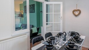 Een eetgedeelte met een tafel voor vier personen, een raam met uitzicht en een hartvormige decoratie aan de muur.