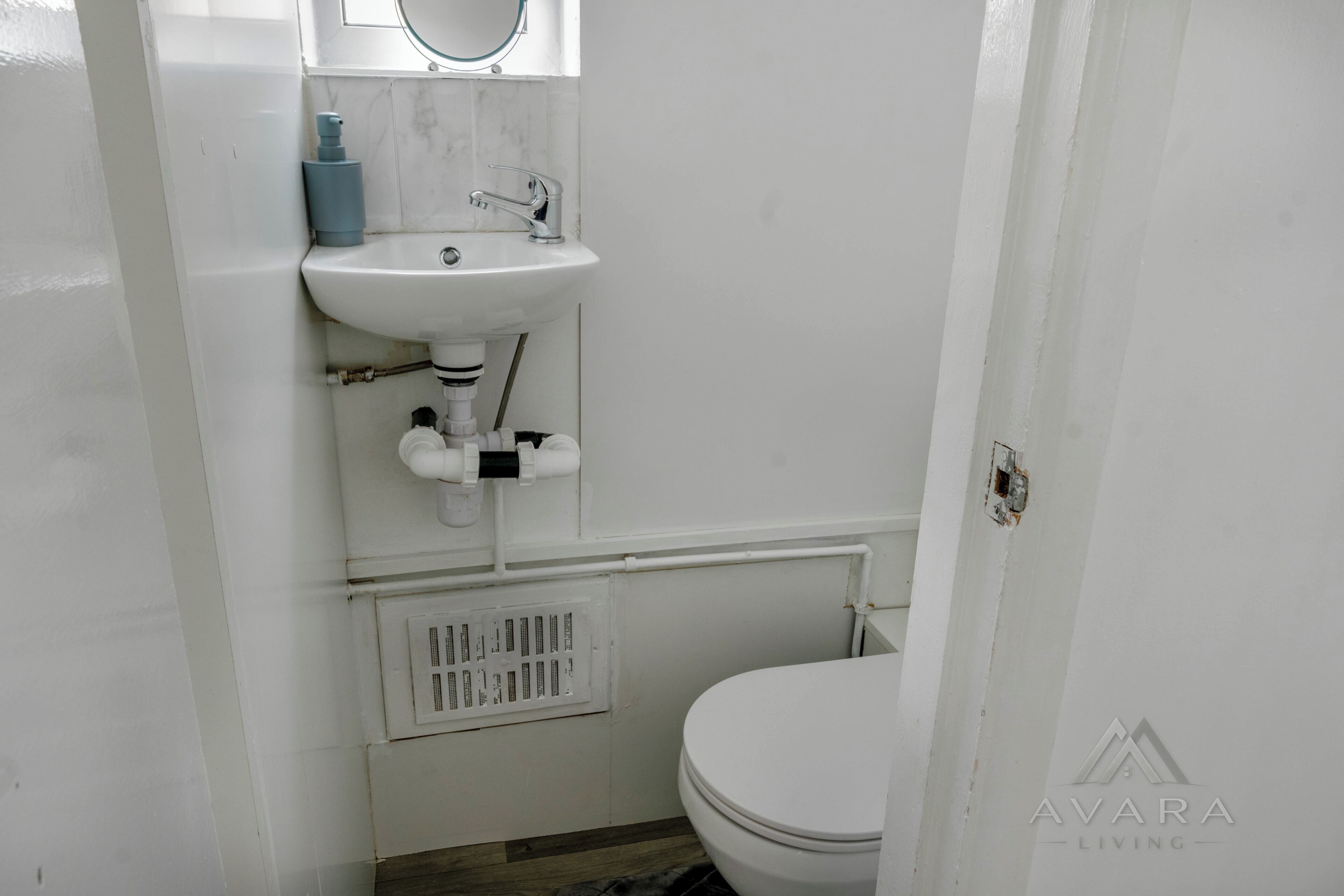 A bathroom with a white sink, a toilet, and a window above the sink.