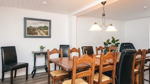 A dining area with a wooden table and chairs, a framed picture on the wall, and a ceiling light fixture. - 12 Person Holiday Home in Ringkobing (Ringkobing)