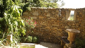 A stone wall with a window, a stone bench, and a small pond. - Mazet Carcarie, vacation home Provence, secluded location, stone house, nature, garden, dog (Montaren-et-Saint-Médiers)