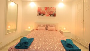 A hotel room with a bed, two bedside tables, a mirror, and a painting on the wall. - Beachfront Penthouse With Pool Access (Marbella)