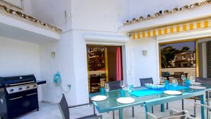 An outdoor dining area with a glass table, chairs, and a grill. - Beachfront Penthouse With Pool Access (Marbella)