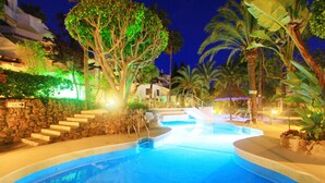 A swimming pool with steps leading down to the water, surrounded by palm trees and a stone wall. - Beachfront Penthouse With Pool Access (Marbella)