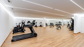 Un gimnasio amplio con diversos equipos de ejercicio, incluyendo cintas de correr y bicicletas estáticas.