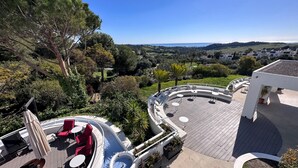 Una terraza en la azotea con piscina, mobiliario exterior y vistas del paisaje circundante.