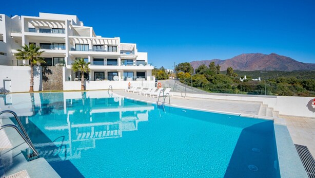 Un hotel moderno con piscina, arquitectura blanca y vistas a la montaña.