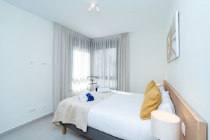 A neatly arranged hotel room with a bed, a bedside lamp, and a window with curtains. - 6-guest Apartment Near Golf Course (Estepona)