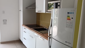 Una cocina con armarios blancos, un refrigerador de acero inoxidable y un microondas.