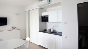 Una cocina moderna con armarios blancos, encimera negra y horno empotrado.